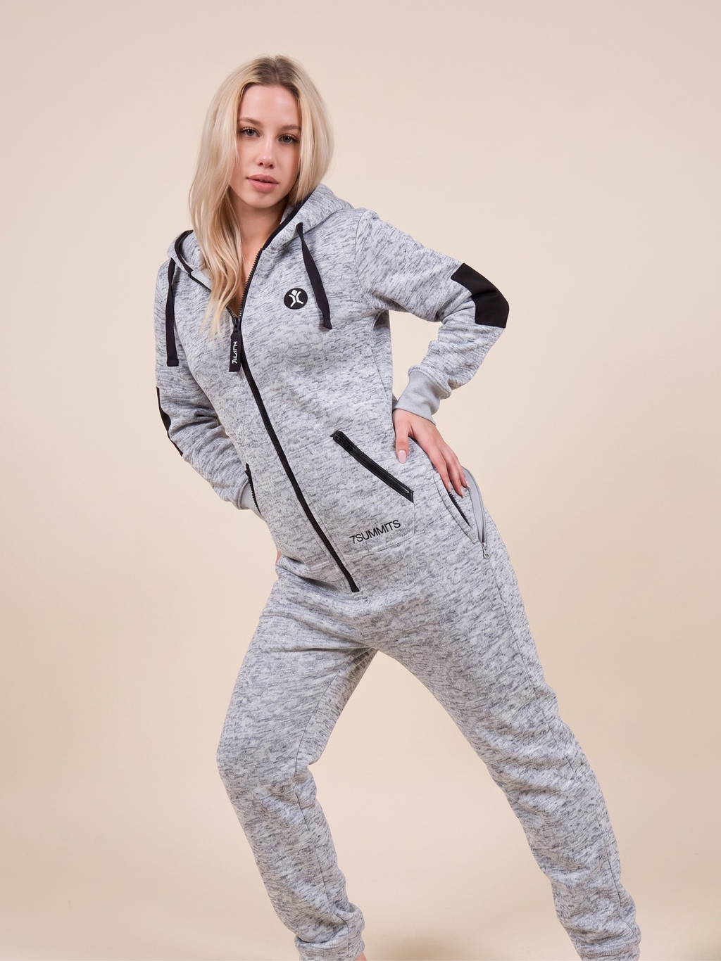 Woman wearing a gray onesie with black accents on a beige background