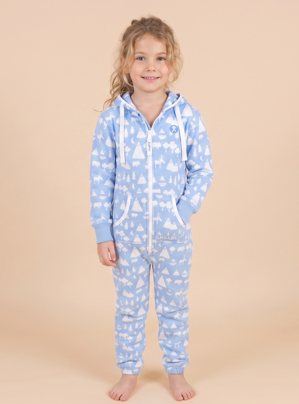 Child wearing a blue onesie with white patterns on a beige background
