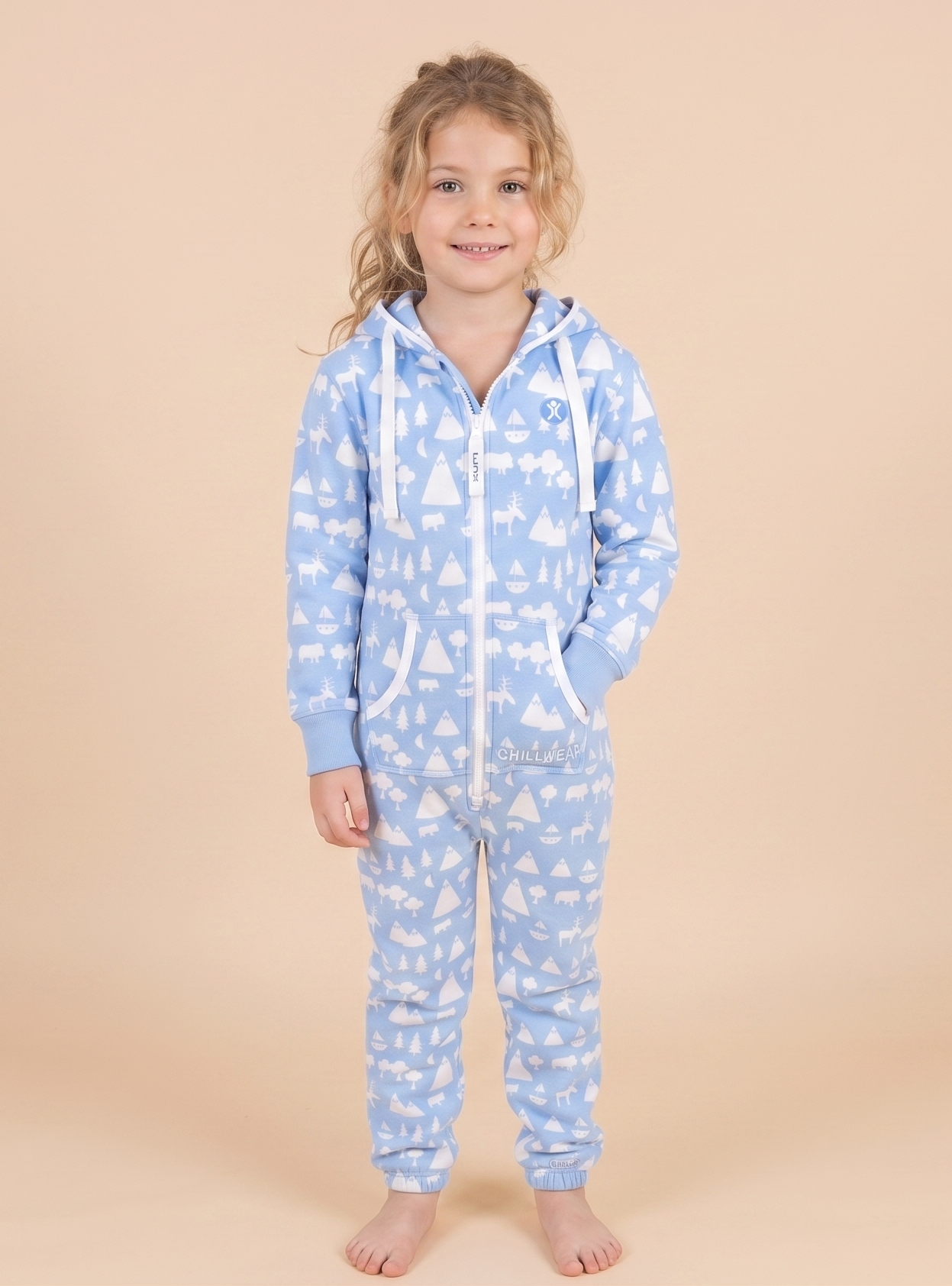 Child wearing a blue onesie with white patterns on a beige background
