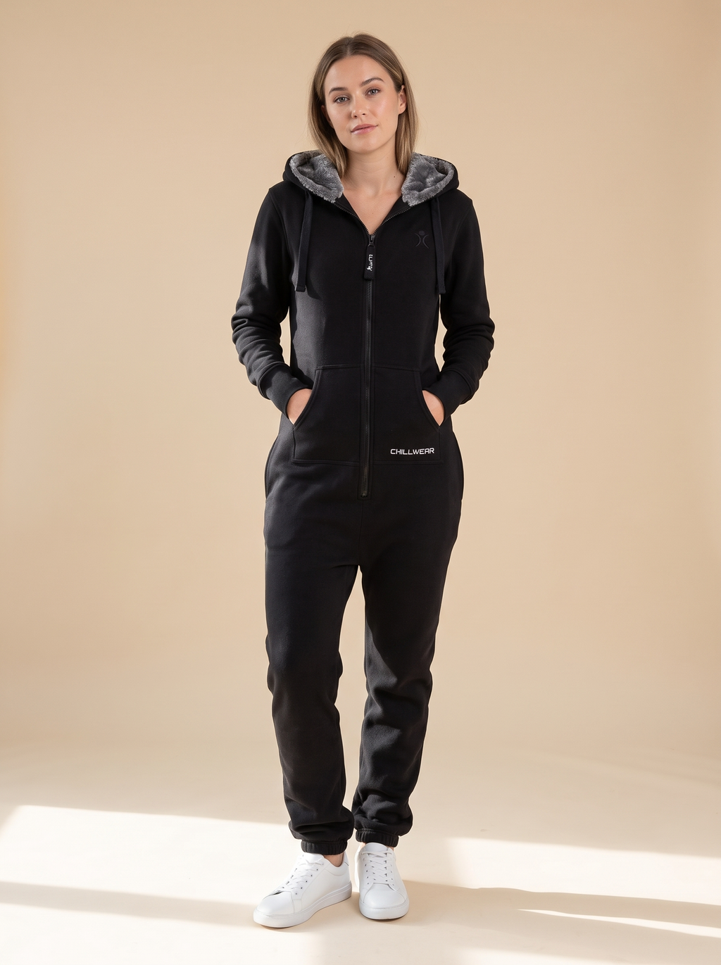 Stealth Black, black fleece onesie with faux fur hood, front view on a woman | Unichill adult unisex jumpsuit designed in Calgary