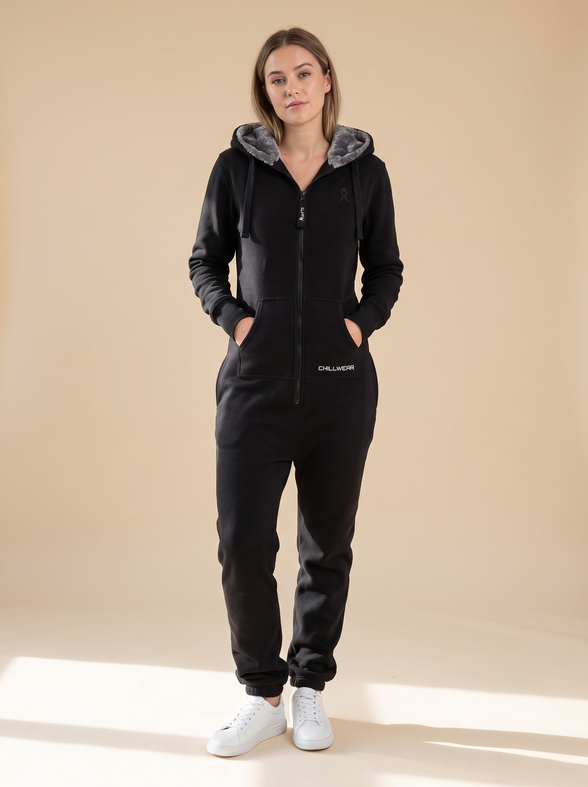 Stealth Black, black fleece onesie with faux fur hood, front view on a woman | Unichill adult unisex jumpsuit designed in Calgary