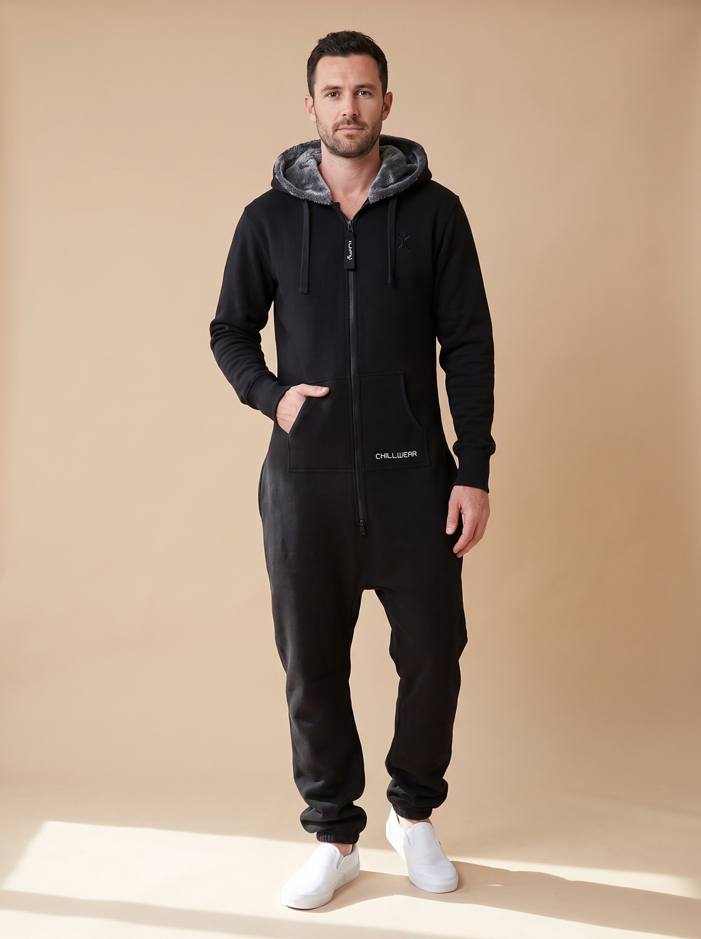 Stealth Black, black fleece onesie with faux fur hood, front view on a man | Unichill adult unisex jumpsuit designed in Calgary
