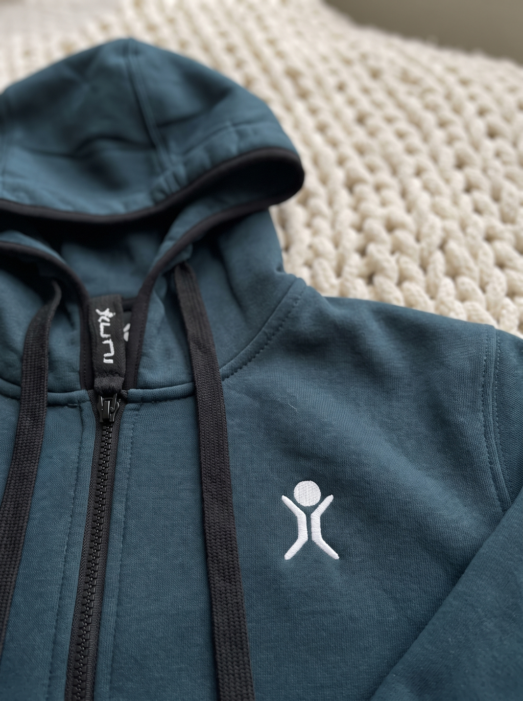 Transformative Teal onesie, close-up of the embroidered logo and UNI zipper pull | Unichill adult unisex fleece onesie designed in Calgary